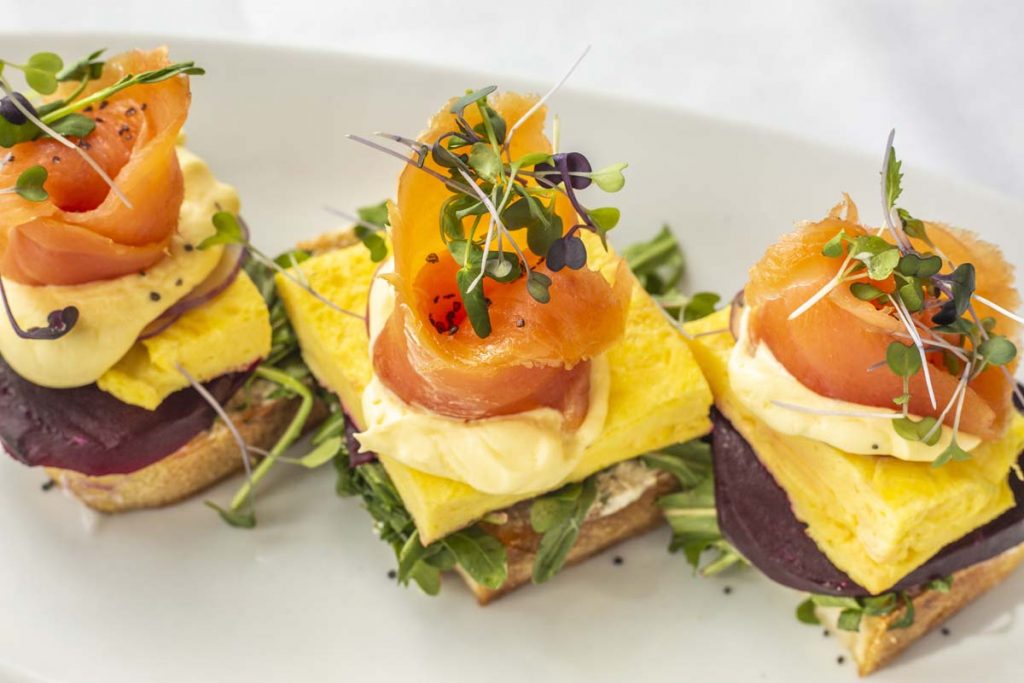 Tucci’s Smoked Salmon Toast brunch entree with thin slices of smoked salmon on scrambled egg and watercress on toast