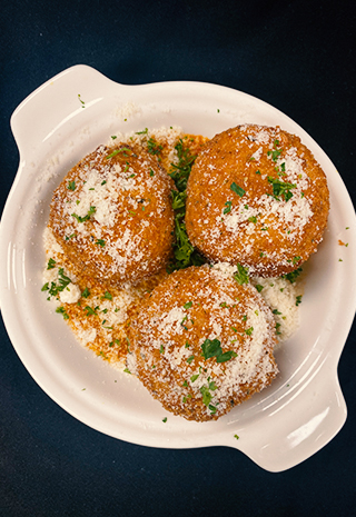 Lobster Arancini - three in a round dish sprinkled with grated cheese